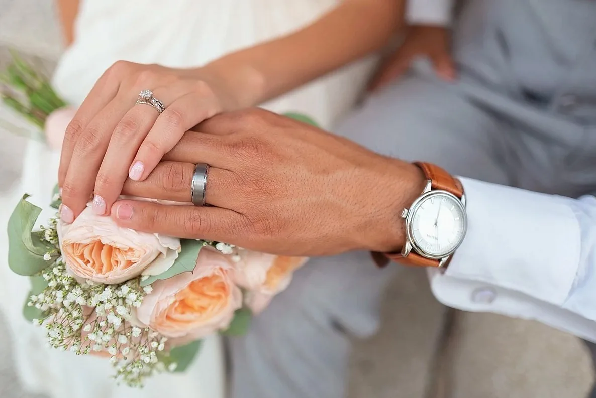 花束を持つ二人の手に重ねた結婚指輪